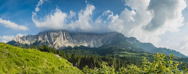 Paisaje alpino con montaña cubierta de nubes y cielo azul en los Dolomitas en Italia.