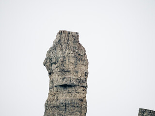 Formación rocosa vertical sobre fondo blanco minimalista