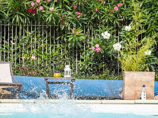 Piscina al aire libre con plantas y flores en un entorno relajante. Salpicaduras después de saltar a la piscina.