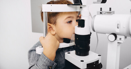 Young boy receiving a thorough eye examination using a slit lamp in a professional ophthalmology...