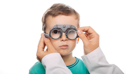 Young boy is being fitted with trial frame glasses while receiving an eye exam by a healthcare professional in a clinic