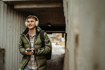 Obraz premium Young adult man student smiling walk to university and listen to music
