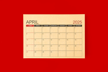 April 2025 desk calendar made from brown paper page on red background.