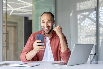 Successful man with phone in hands celebrating victory and triumphant achievement results....