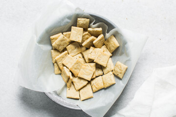 Overhead view of homemade crackers in a parchment lined bowl, top view of freshly baked cracker biscuits in a bowl, process of making crackers