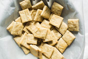 Overhead view of homemade crackers in a parchment lined bowl, top view of freshly baked cracker biscuits in a bowl, process of making crackers