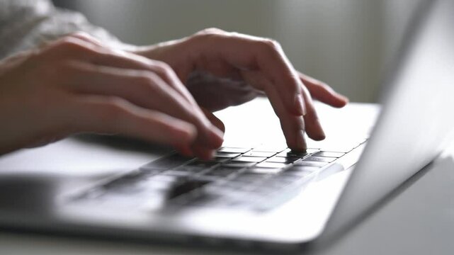 Close-up of a woman's hands typing on a keyboard using an artificial intelligence laptop chatbot