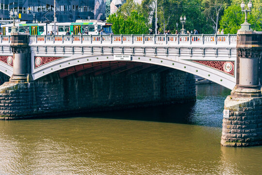 An electric tram crossing an historic arched bridge over a river