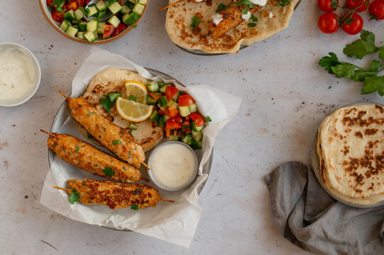 Chicken Kofta Kebab on wooden skewers with pita, garlic sauce Toum, parsley, lemon, cucumber and tomato. Shish kafta tavuk. Traditional Middle East food. Lebanese, Turkish cuisine. Food photography.