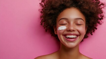 A joyful expression radiates from a natural curly-haired person wearing under-eye patches against a pink background, embodying genuine happiness and self-care in modern beauty.