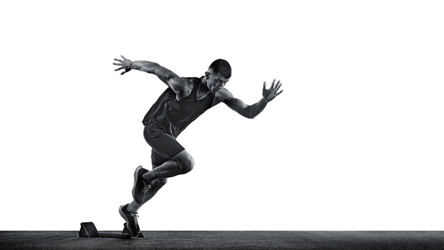 Dynamic photo of young sportsman, sprinter running from start line against white background. Monochrome photo. Concept of sport, healthy lifestyle, championship, action. Ad