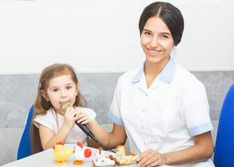 Young child engages in speech therapy while using a microphone and playing with toys in a warm...