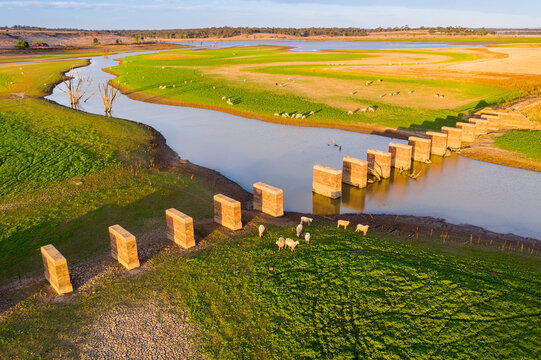 Aerial view of a sheep around a row of brick pillars crossing river