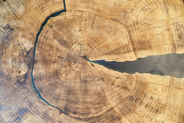 Wooden tabletop with natural rings and cracks filled with epoxy resin, creating abstract background