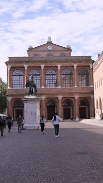 Historic building in Rimini, Italy, with a statue in the foreground and people walking. A beautiful travel destination showcasing Italian architecture, culture, and heritage. 