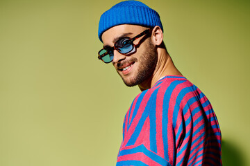 Young man showcases vibrant fashion sense with stylish outfit and sunglasses in studio