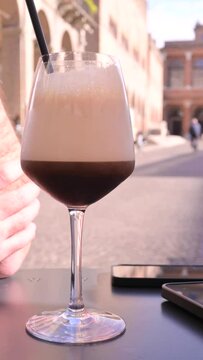 Iced Italian espresso with a creamy foam, served in a wine glass at an outdoor caf&eacute;. A refreshing and elegant coffee experience in Italy, perfect for summer and coffee lovers. High quality FullHD 