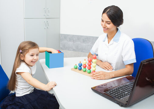 A child engages joyfully with colorful toys while an occupational therapist facilitates skills development through play at a therapy center