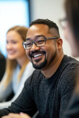 Obraz premium A middle-aged man with glasses is laughing at a joke during an office meeting. He's wearing casual clothing and enjoying the positive energy of the group discussion.