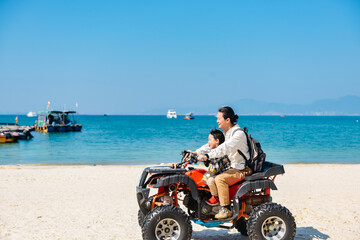 Asian kid and dad riding ATV at in Xunliao Bay, Huizhou city, Guangdong Province, China, during January © sweetriver