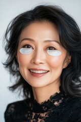 A happy, confident Asian woman wearing decorative eye masks, embracing a modern and unique beauty trend.