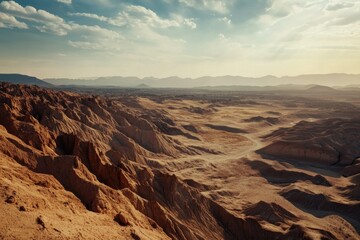 Naklejka premium The vast expanse of a desert landscape under the warm glow of a setting sun, with rocky cliffs and earthy tones dominating the scene.