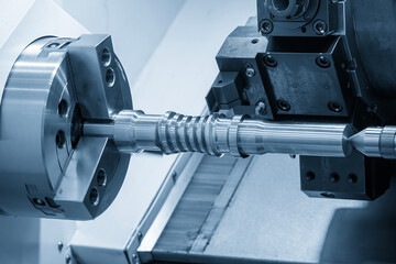 The  CNC lathe machine forming  cutting the metal screw shaft parts in the light blue scene.