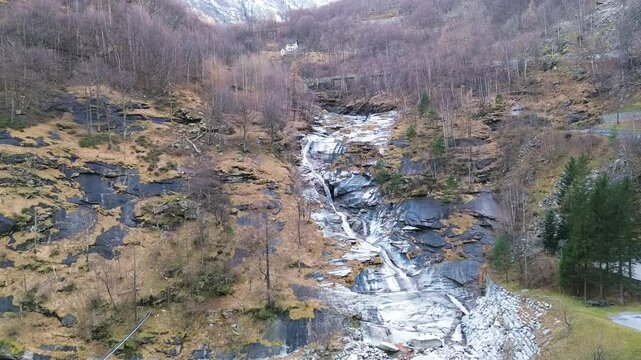 Spring waterfall cascading down rocky slopes in a scenic mountain landscape. Melting snow feeds the rushing water, creating a breathtaking view of nature's power and beauty. High quality FullHd