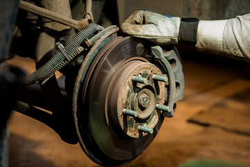 Close-Up Inspection and Maintenance of Rusty Car Brake System by Mechanic Wearing Protective Gloves