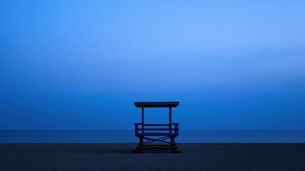 Tranquil Beach Scene at Dusk with a Lifeguard Stand Silhouetted Against the Ocean Horizon