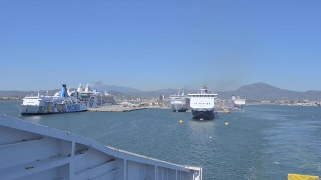 Ferry arriving at a busy port with ships, mountains, and clear blue sky in the background. A maritime scene capturing travel, transportation, and sea adventure. High quality FullHD footage