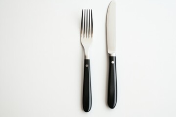 Cutlery set featuring a fork and knife on a minimalist table setting with black handles and a light background