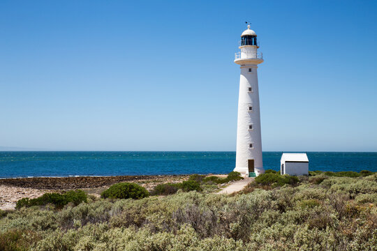 lighthouse with blue water and cloudless sky