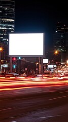 Illuminated blank billboard at night in urban setting with blurred traffic lights streaks