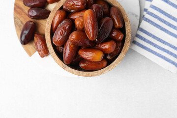 Tasty dried dates in bowl on white table, top view. Space for text