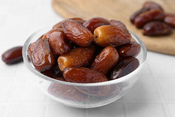 Tasty dried dates in glass bowl on white table, closeup