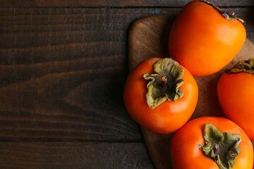 Delicious ripe juicy persimmons on wooden table, flat lay. Space for text