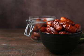 Tasty dried dates in bowl and jar on wooden table, closeup. Space for text