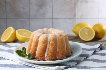 Tasty lemon cake with glaze and mint on table