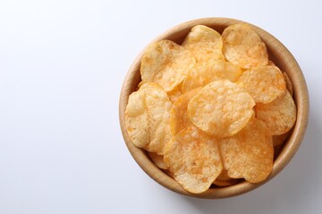 Tasty potato chips in bowl on white background, top view. Space for text