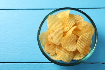 Tasty potato chips on blue wooden table, top view. Space for text