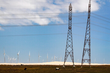 A group of wind turbines and power transmission towers located in the dunes of Paulino Neves, MA, northeastern Brazil