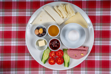 Traditional Turkish breakfast plate. The plate contains cheese varieties, jam, honey, eggs, tomatoes, cucumber, butter, olives and salami.