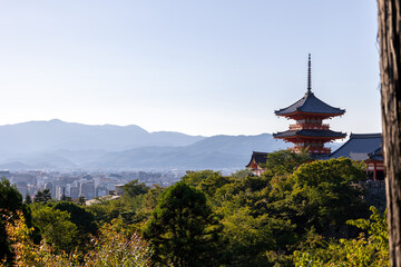 Japanese Historic temple stands among lush greenery with mountains in the background during clear daylight Kiyomizu-dera