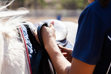 riding instructor changing stirrups on saddle