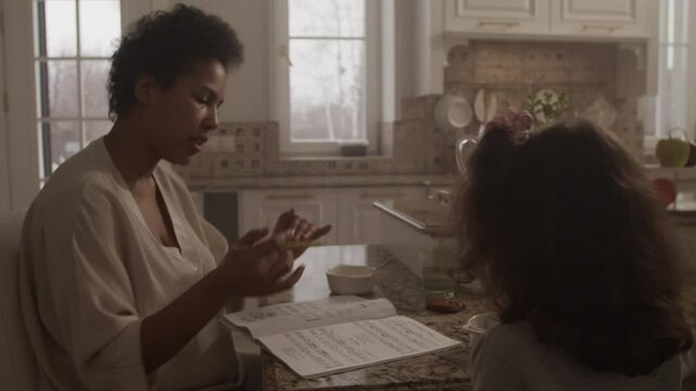 Black woman singing solfeggio music along with daughter at table