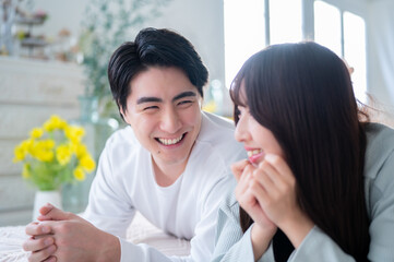 うつ伏せで笑顔で話す日本人男女