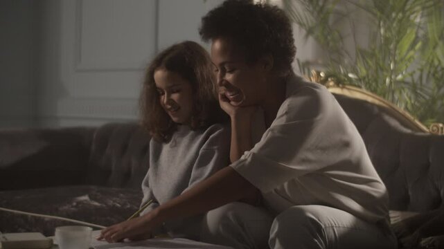 Black woman sitting on sofa teaching daughter solfeggio music