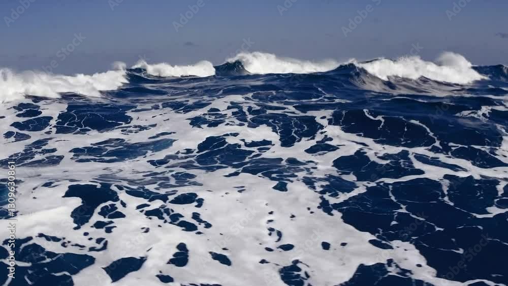 Poster dark blue ocean waves are crashing and creating white foam on a sunny day with clear sky, creating a