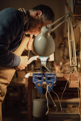 Luthier working on violin scroll with precision in his workshop